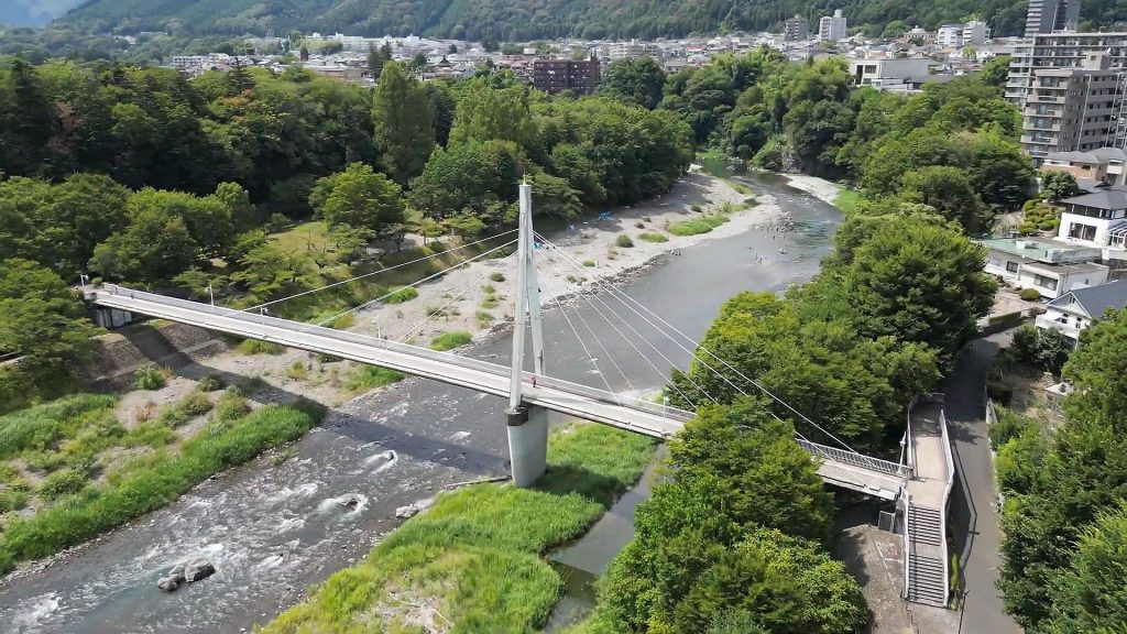 釜の渕公園内の鮎美橋と青梅の街並み